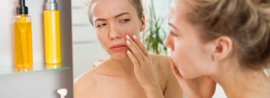 A Woman watching her face in the mirror | Get Eye fillers in Beauty Boost Med Spa at Newport Beach, CA