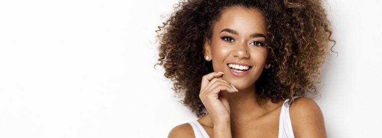 Curly hair lady smiling pleasantly | Dermal fillers in Beauty Boost Med Spa at Newport Beach, CA