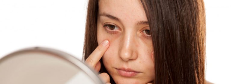 A Lady looking dull eyes in mirror | Get Eye filler on Beauty Boost Med Spa in Newport Beach, CA