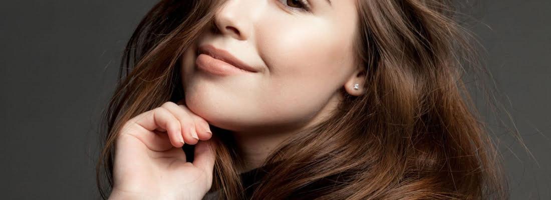 A Girl holding hand near the neck with a cute smile | Chin Fillers in Beauty Boost Med Spa at Newport Beach, CA